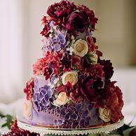 Create a whimsical, multi-tiered wedding cake that is entirely covered in delicate blooms of vibrant purple and ruby red flowers.