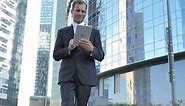 Walking Businessman Using Tablet While Walking Outside Office
