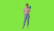 Free stock video - Full length studio portrait of woman holding blue screen mobile phone towards camera against green screen 2