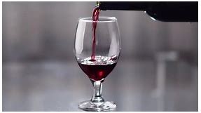 Close-up of wine being poured from a bottle into a glass, camera movement, rack focus