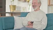 Excited Old Man Watching TV on Sofa