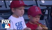 Kid struggles to eat a hot dog at baseball game