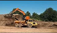 Hitachi 225 excavator at work loading tipper trucks