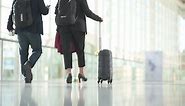 Premium stock video - People in business outfits walking with luggage in a bright hall