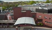 Aerial pullback reveals hospital Emergency Room entrance. Healthcare in America. Exterior of brick m