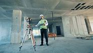Construction worker is regulating land surveying equipment at a construction site