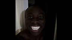 Black man smiles in dark laughing