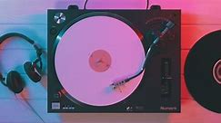 Varna, Bulgaria - April 2018, turntable Numark: Vinyl Retro Top view musical DJ record player rotating white vinyl plate stylus needle wooden background, headphones blue-red neon light. Loop. Disco
