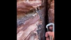 USA: Rock climber clips carabiner on unusual rock hole in Las Vegas expedition