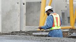 African american mason worker pouring the ready-mixed concrete at Heavy Industry Manufacturing Prefabricated concrete walls factory