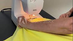 4K HD video of older caucasian female hands working with sewing machine, sewing border edge on flannel blanket. Coming to a corner, turning and resuming sewing, removing pins as she works.