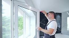 worker installs and adjusts a new plastic window in house. repair regulates Installation and adjustment Workman in overalls installing or adjusting plastic windows in room at home. maintenance service