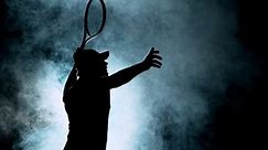 Super slow motion of tennis player silhouette hitting ball. Smoke effect around, black background. Filmed on high speed cinema camera, 1000fps.