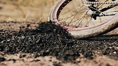The bicycle wheel makes a sharp turn on a dirt road. Close-up shooting in slow motion