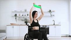 Delighted Caucasian female working out with stretching bands while staying in good mood on sunny day at home. Smiling mature person increasing endurance while doing exercise with disability.