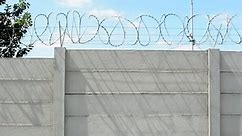 tall concrete block wall with barbed wire in the countryside