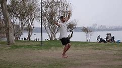 The guy walks on the tape (sling). Slacklining in the park. The sea is in the background.
