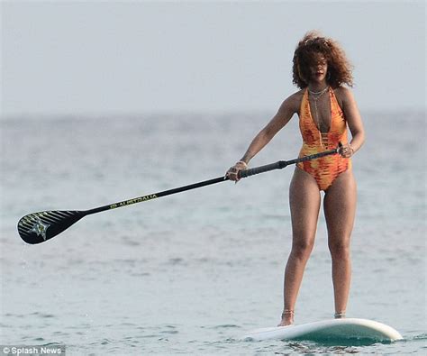 rihanna showcases her curves in a flame coloured swimsuit