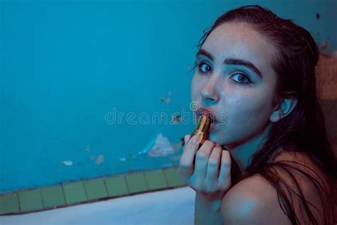 playful brunette posing in a bathtub wearing underwear in the neon