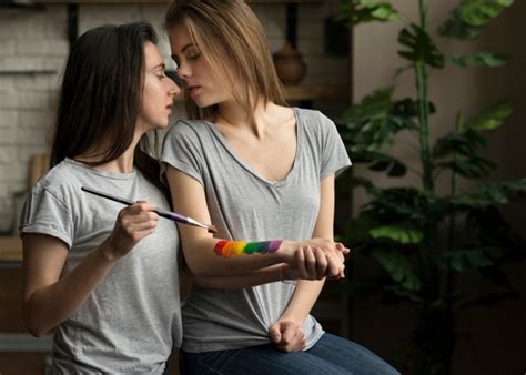 romántica pareja de lesbianas jóvenes sosteniendo la bandera del arco
