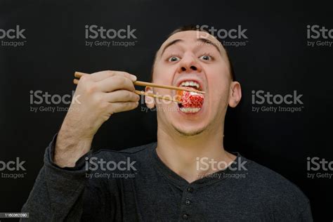 hungry man eats rolls with chopsticks open mouth black background stock