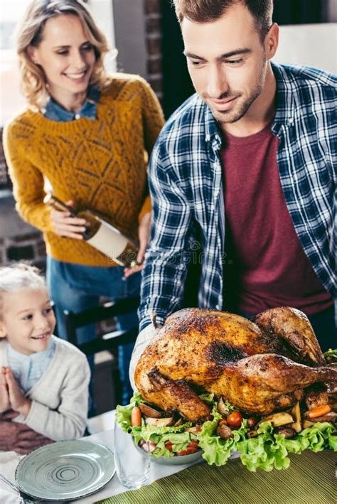 handsome young father putting thanksgiving turkey  holiday table  excited wife