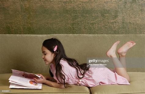 girl reading storybook on sofa barefoot foto stock getty images