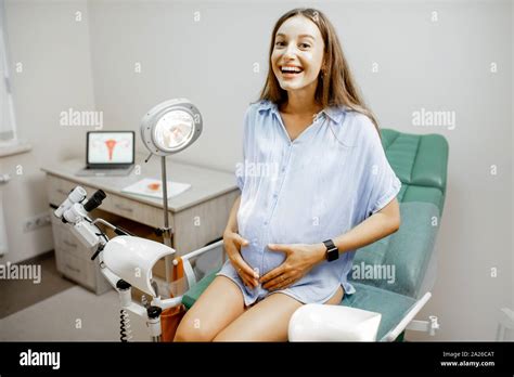 Smiling Pregnant Woman Sitting On The Gynecological Chair Before A