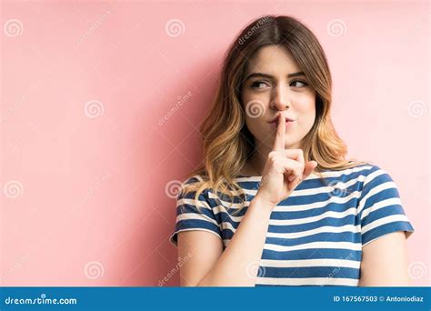 Beautiful Female Making Silence Gesture Against Plain Background Stock