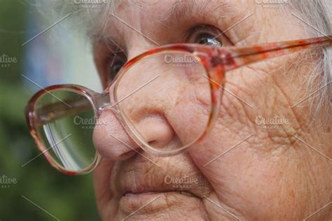 old woman straightens her glasses and looking forward portrait of