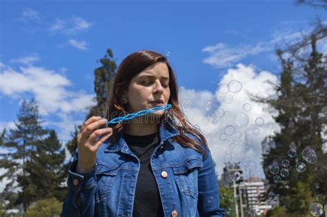 Beautiful Hispanic Woman Blowing Soap Bubbles In The Middle Of A Park