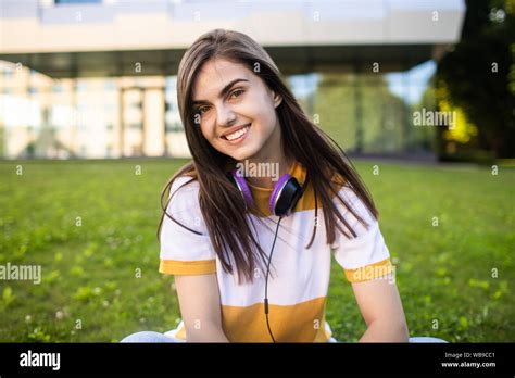 Portrait Of Smiling Cute College Girl With Headphones Posing In Front