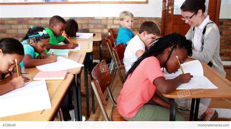 Pupils Working Hard During Class With Teacher Smiling At Camera Stock