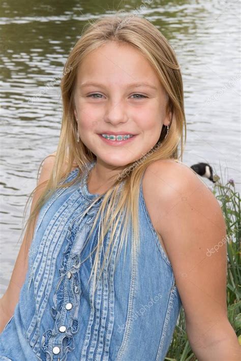 blond preteen girl in blue dress close up summer photo on the green garden background — stock