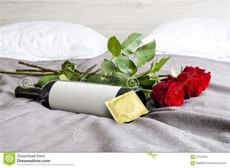 bottle of wine roses and condom on bed set stock image