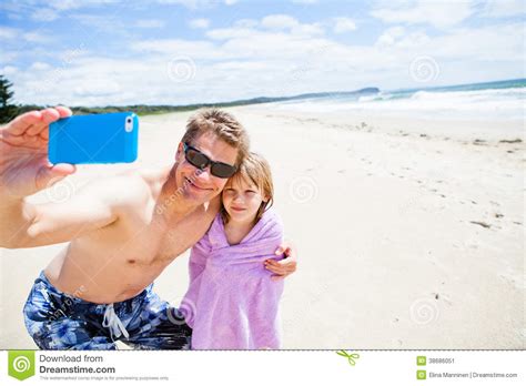 Father Taking Photograph With Daughter At Beach Stock