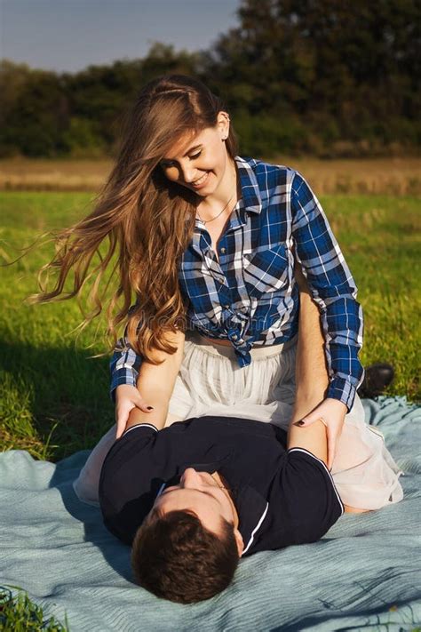 Девушка сидит на парне на пикнике Стоковое Фото изображение