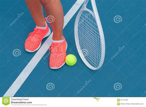 Female Feet In Sneakers With Tennis Ball And Racket On