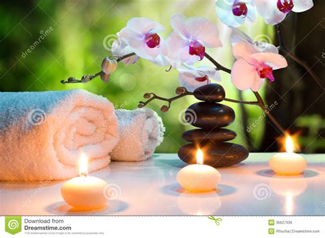 massage composition spa with candles orchids and black stones in