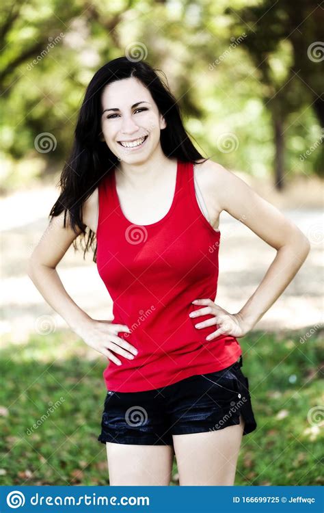 smiling hispanic teen woman outdoors red top and shorts