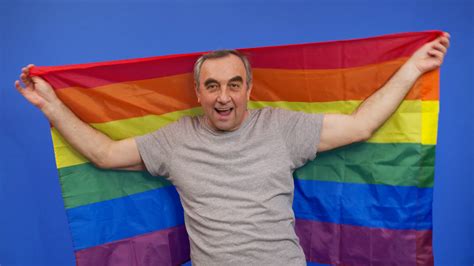elderly man holding with lgbt pride flag alone one covering lgbt