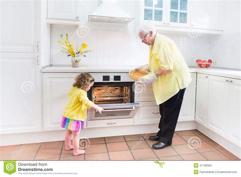 Grandmother And Sweet Girl Baking Pie In White Kitchen Stock Image