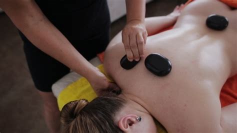 masseuse using hot stone massage therapy on a beautiful aucasian client