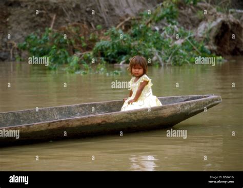 small girl sitting in a dugout canoe on the amazon river peru stock