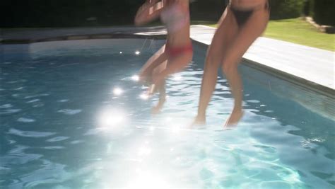 mother and daughter jumping into swimming pool stock