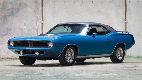 blue muscle car parked  front   concrete wall