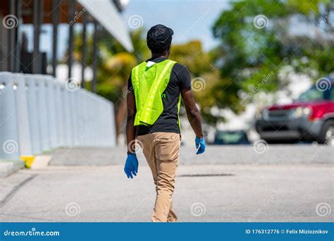 supermarket employee wearing blue gloves walking outdoors   parking lot editorial photo
