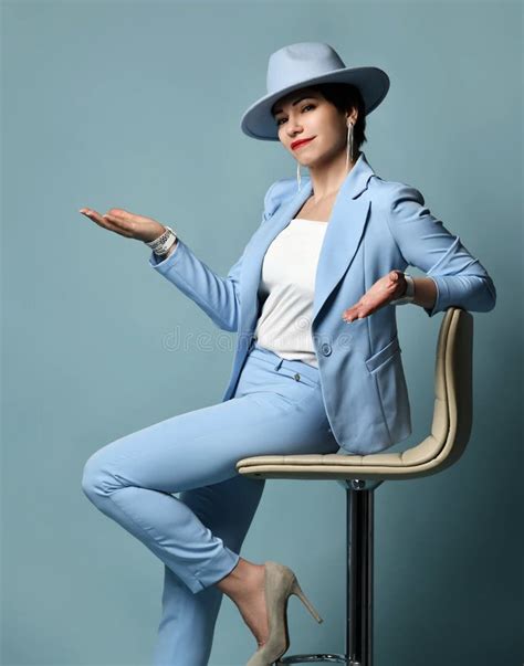 Smiling Short Haired Brunette Woman In Blue Business Suit And Hat Sits