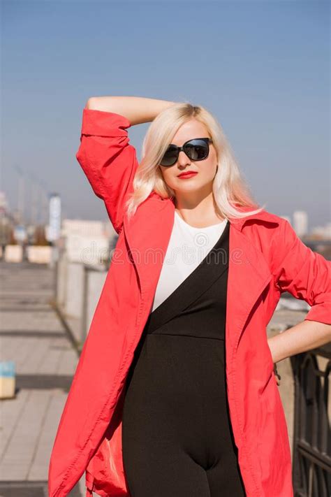 attractive blonde model posing in black coat wears sunglasses on stock
