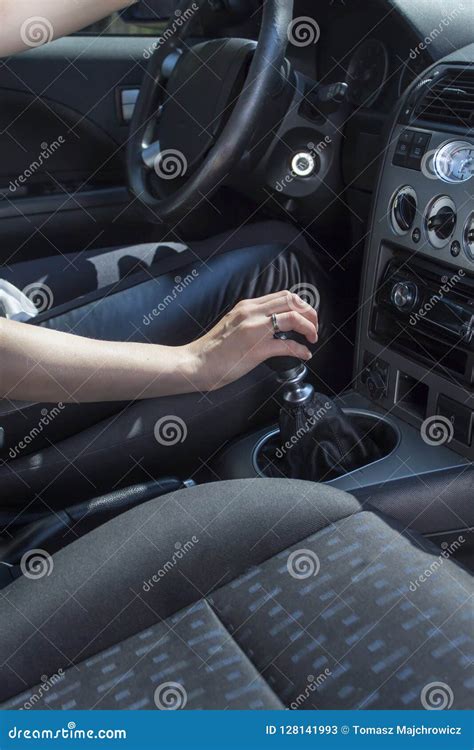 The Woman Sitting Behind The Wheel Of The Car Holds A Hand On The Gear